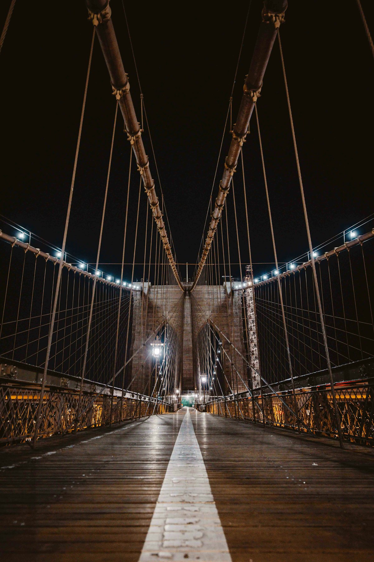 Suspension bridge cables supporting a walkway at night.